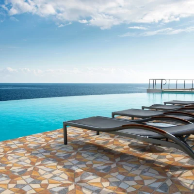 Piscina vista al mar, ambiente soleado, asientos negros y piso de cerámica piedra Artexa, colección Ecos, Cerámicos Gala