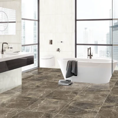 Baño iluminado con bañera blanca, ducha con recubrimiento de cristal y piso de cerámica mármol Regent Brown, colección Ecos de Cerámicos Gala